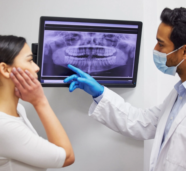 Dentist showing a patient her impacted wisdom tooth on a dental X-ray